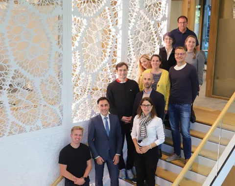 Gruppe von Studierenden und Dozenten des Executive Master of Laws (LL.M.) im Wirtschaftsstrafrecht auf einer Treppe, umgeben von dekorativen Wandpaneelen, während einer Studienreise in Den Haag.