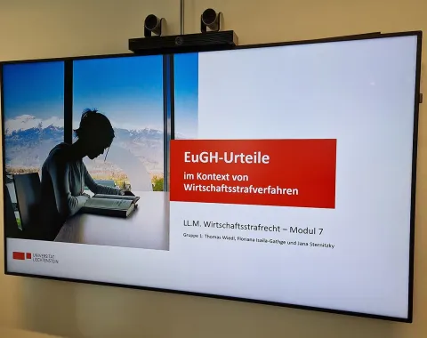 Ein Bildschirm zeigt eine Präsentation mit dem Titel "EuGH-Urteile im Kontext von Wirtschaftsstrafverfahren". Links ist eine Person am Laptop vor einem Fenster mit Bergblick zu sehen. Unten steht "LL.M. Wirtschaftsstrafrecht – Modul 7" und die Namen der Gruppenmitglieder.