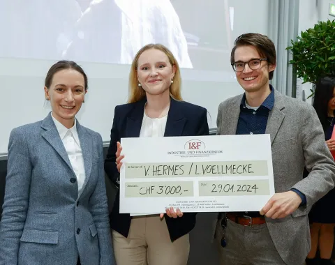 Drei Personen halten einen großen Scheck mit der Aufschrift "I&F Family Wealth Preservation Award" in einem Veranstaltungsraum. Sie lächeln in die Kamera.