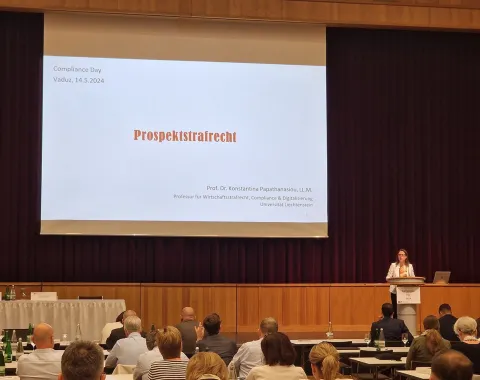 Eine Person hält einen Vortrag auf dem Compliance Day 2024 im SAL in Schaan. Auf der Leinwand steht "Prospekthaftungsrecht". Im Publikum sitzen zahlreiche Teilnehmende.