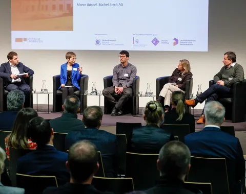 Podiumsdiskussion an der Universität Liechtenstein mit fünf Personen auf einer Bühne, die vor einem Publikum über Nachhaltigkeitsthemen sprechen. Im Hintergrund ist eine Präsentation zu sehen.