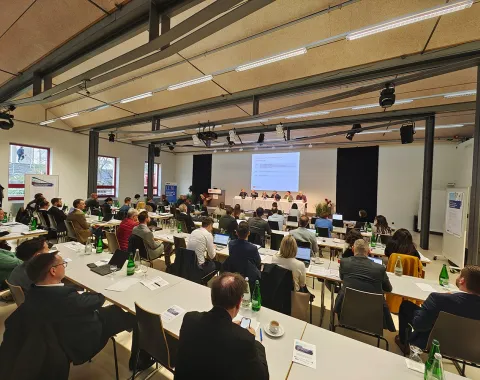 Ein Auditorium der Universität Liechtenstein, gefüllt mit Teilnehmenden der Liechtenstein Trust Conference 2024. Vorne eine Präsentation auf einer Leinwand, umgeben von Vortragenden. Die Teilnehmenden sitzen an Tischen mit Getränken und Notizen.