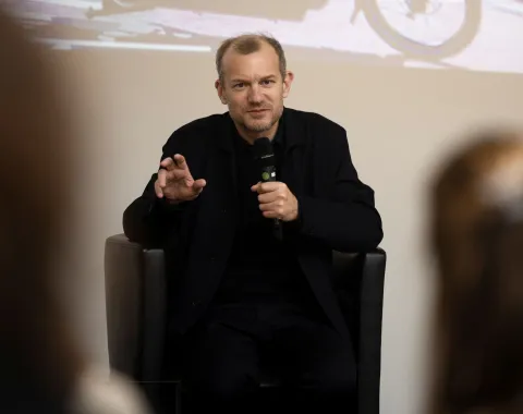 Vortragender mit dunkler Kleidung und einem Mikrofon in der Hand