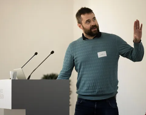 Mann mit blauem Pullover bei einem Vortrag