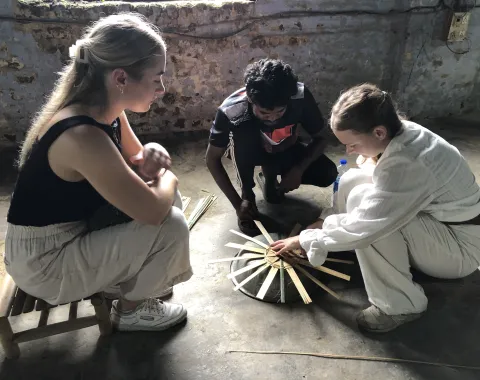 Drei Menschen mit einem kleinen Modell in der Mitte