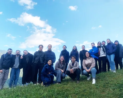 Gruppenfoto junger Studierender mti blauem Himmel und grüner Wiese