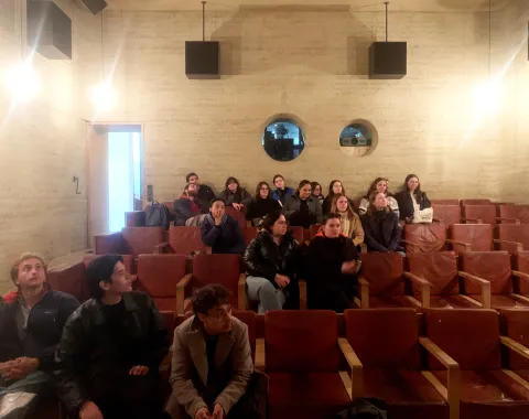 Junge Menschen in einem Kino aus Stampflehm mit braunen Ledersesseln