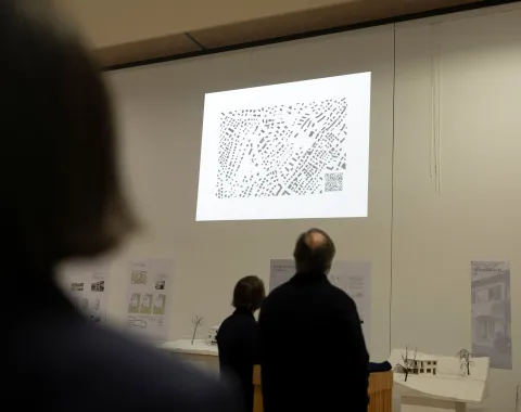 Mehrere Menschen schauen auf eine Leinwand mit einem Plan