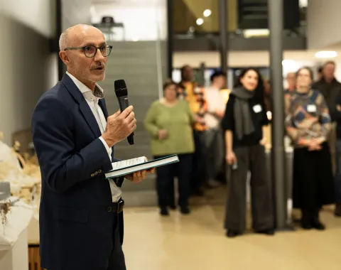 Ein Mann präsentiert vor einer Gruppe von Menschen mit einem Mikrofon in der Hand