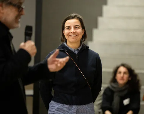 Eine Frau mit dunklen Haaren und dunkelblauem Pullover 