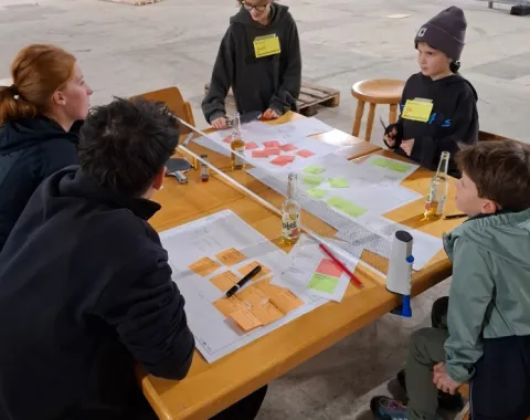 Mehrere Kinder arbeiten mit bunten Notizzetteln an einem Holztisch