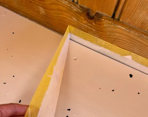 Malerkrepp wird von einer Holzwand abgezogen