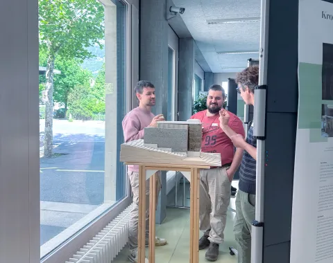 Ein Architekturmodell auf einem Sockel mit Menschen, die sich unterhalten im Hintergrund