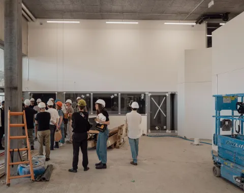 Eine Gruppe von Menschen mit Bauhelmen, die auf einer Baustelle geführt werden. 