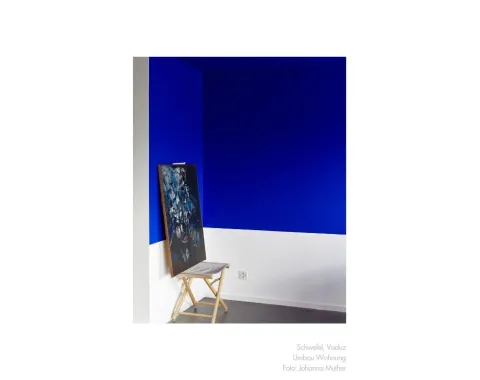 Blau-weisse Wand mit einem Stuhl und einem Bild darauf 