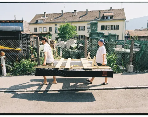 Zwei junge Männer transportieren ein selbstgebautes Boot. 