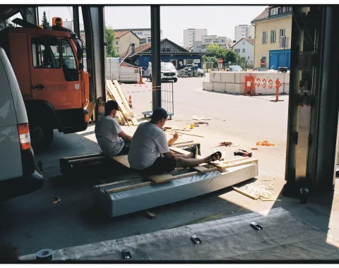 Zwei junge Männer sitzen in einer Werkstatt auf einem selbstgebauten Boot
