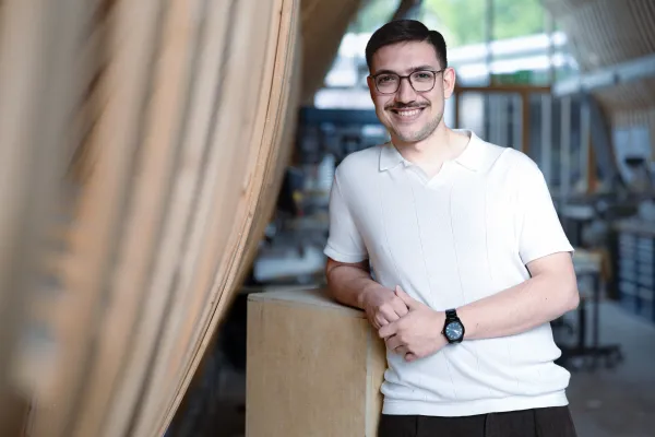 Studierender des Master Architektur der Universität Liechtenstein mit weissem T-Shirt steht in der Modellwerkstatt