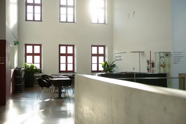 Bright Cafeteria Interior with High Ceilings, Red Windows, and a Glass Display Case with a Trophy