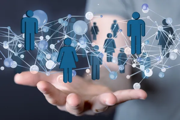 Handfläche mit schwebenden Symbolen für Menschen und Netzwerke, Darstellung von digitaler Vernetzung und sozialem Austausch.