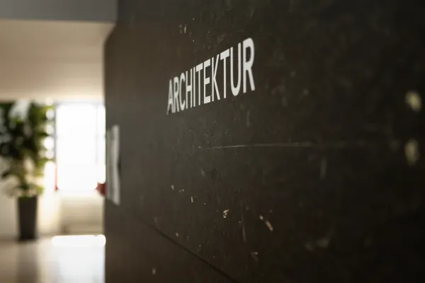 Beschriftung „Architektur“ auf dunkler Wand im Gebäude der Universität Liechtenstein.