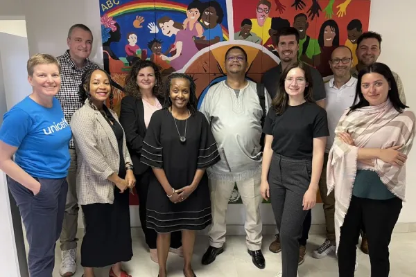 Eine Gruppe von Menschen steht lächelnd vor einem bunten Wandgemälde. Sie sind Teil einer Delegation der Universität Liechtenstein und Partnerorganisationen, die an einer Expedition nach Südafrika teilnehmen, um nachhaltige Finanzlösungen zu entwickeln.