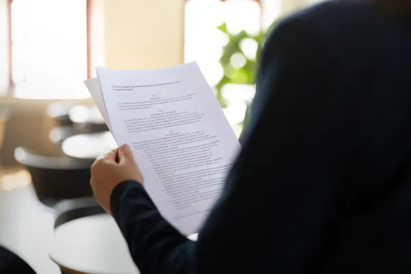 Person hält ausgedruckte Dokumente mit wissenschaftlichem Text.
