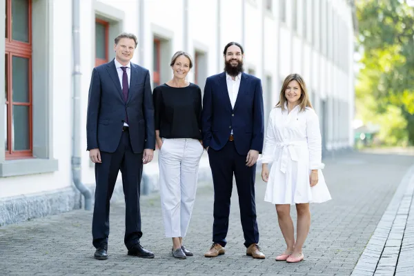 Vier Personen im Business Outfit vor dem Gebäude der Universität Liechtenstein.