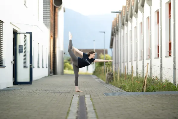 Frau in Yoga-Pose auf dem Campus der Universität Liechtenstein im Freien.
