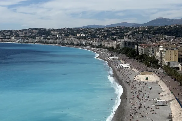 Grau wirkender Strand mit Blauem Wasser und vielen Menschen