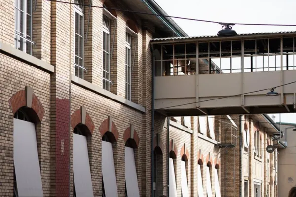 Mehrere Menschen laufen neben einem alten Fabriksgebäude