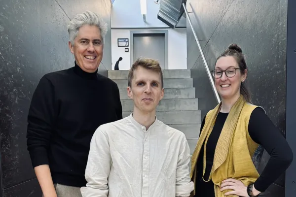 Drei Personen auf einer grau/schwarzen Treppe