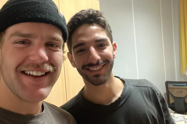 Zwei Studierende halten lächelnd Getränkedosen in die Kamera.