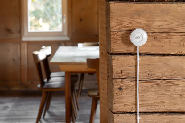 Ein weisser Lichtschalter an einer Altholzwand