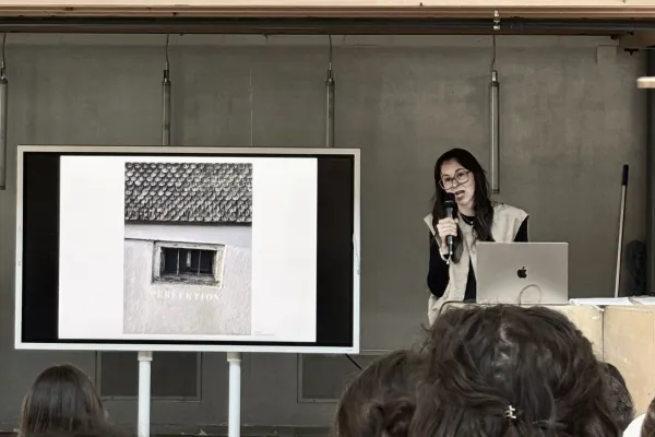 Vortragssituation mit einem Bildschirm und einer vortragenden Person