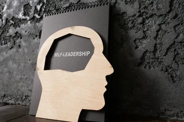 Stilisierter Kopf aus Holz mit Beschriftung Self Leadership