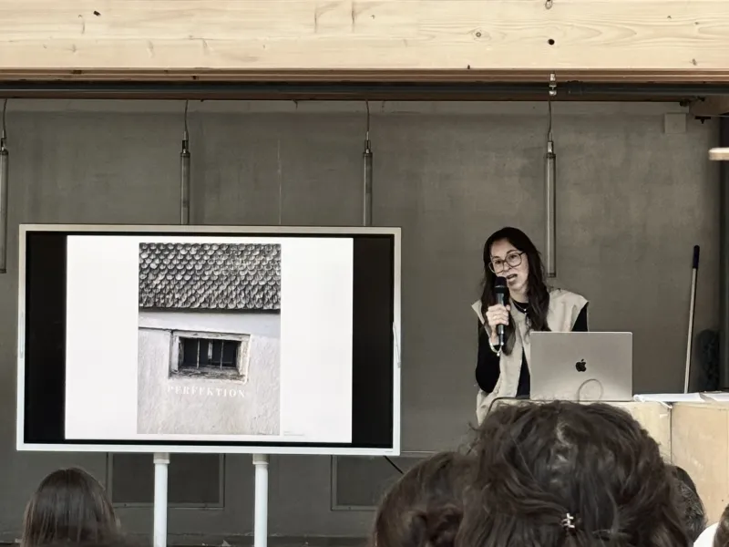 Vortragssituation mit einem Bildschirm und einer vortragenden Person