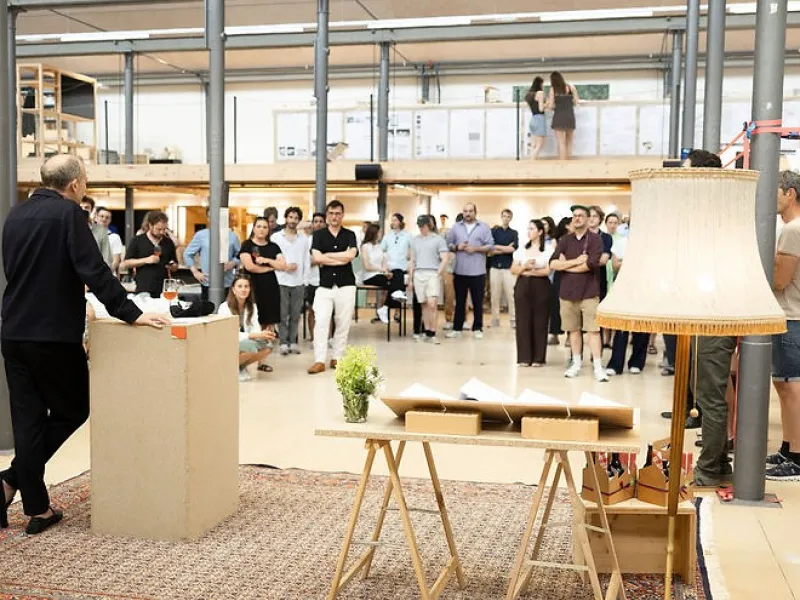Publikum hört Mann mit Mikrofon in einem grossen Atelier zu 