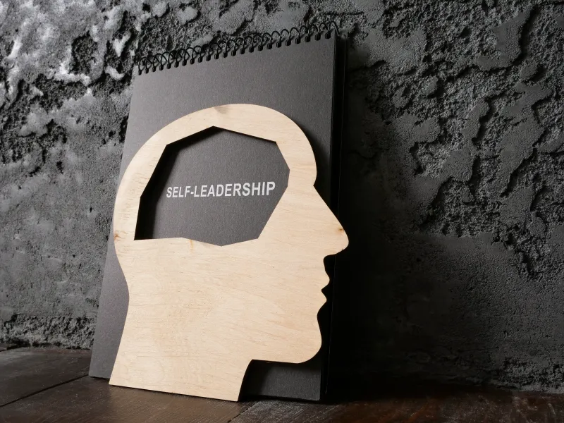 Stilisierter Kopf aus Holz mit Beschriftung Self Leadership